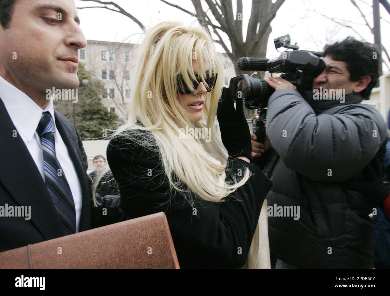 Anna Nicole Smith, center, tries to shield herself from cameras as she