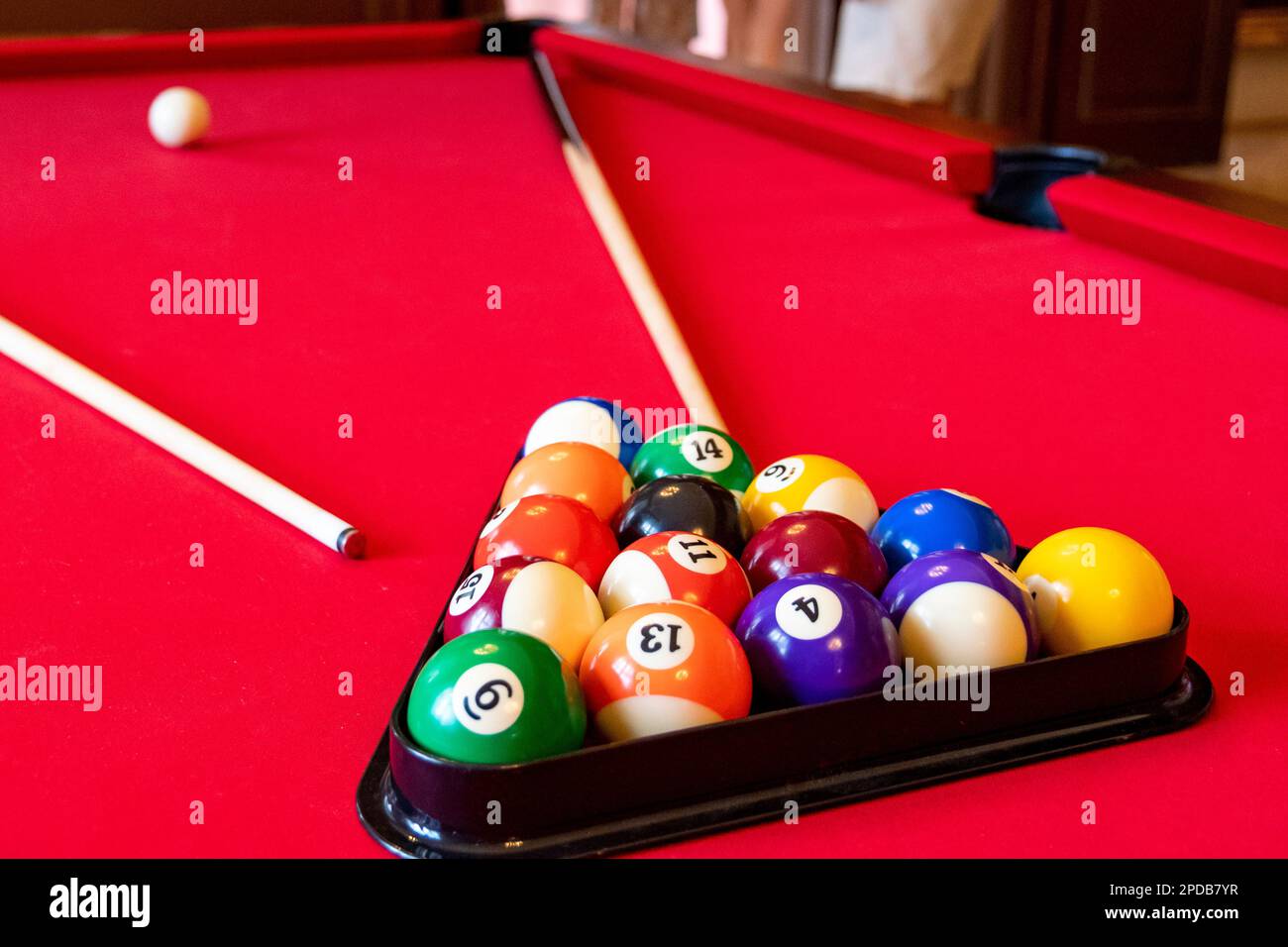 Table de billard rouge avec boules et queues de billard Banque D'Images