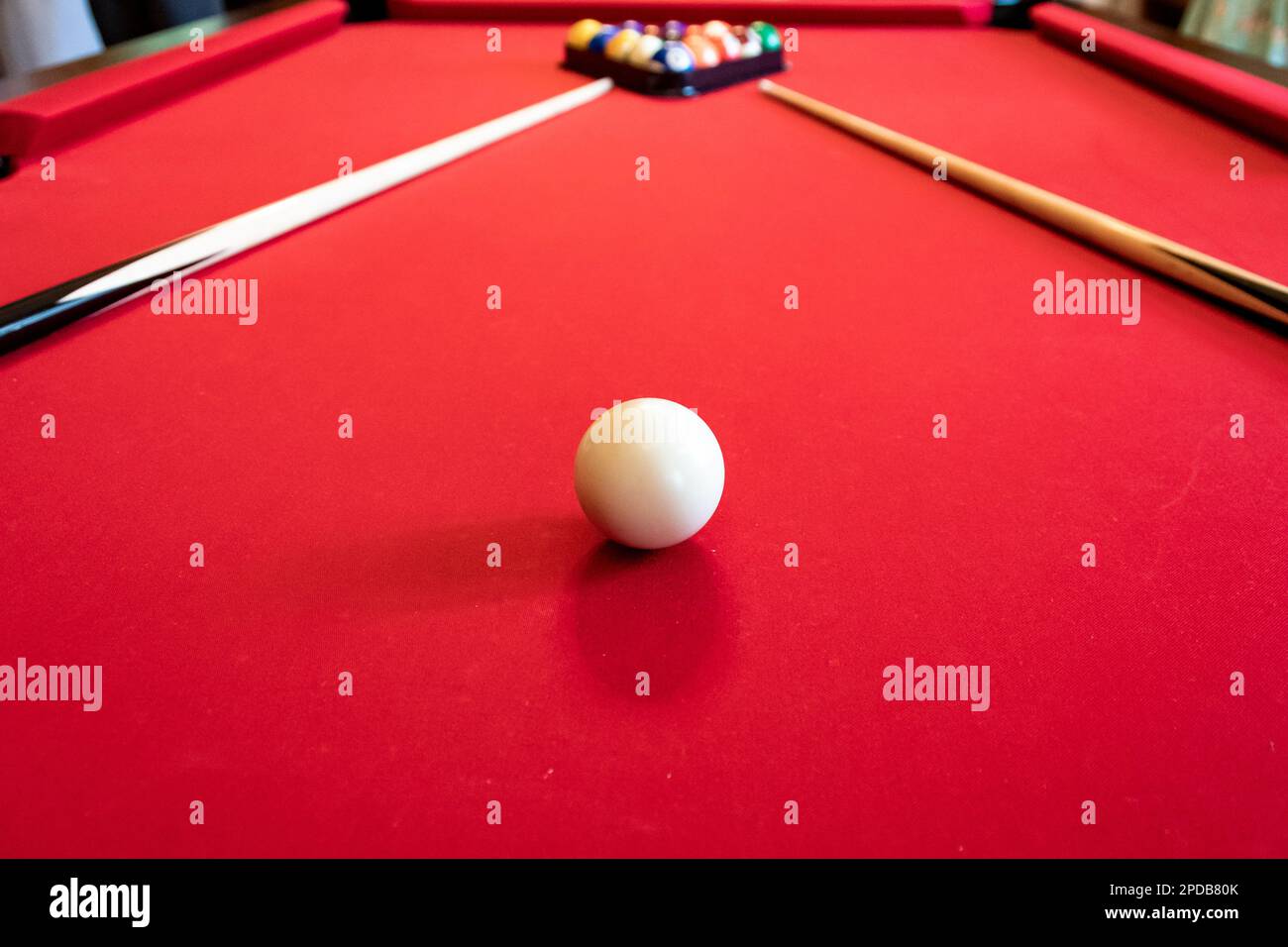 Table de billard rouge avec boules et queues de billard Banque D'Images