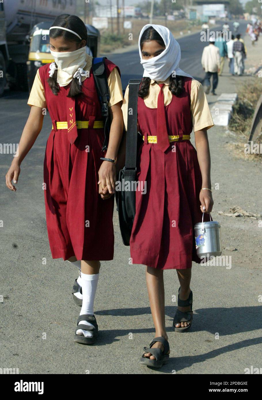 Students go back home from school with their faces covered at Navapur, in the western Indian state of Maharashtra, Friday, Feb. 24, 2006. Workers disinfected farms and chicken coops Friday in a small western town hit by India's first outbreak of bird flu, a day after the slaughter of all birds in the sprawling poultry farming region was completed. (AP Photo/Rajesh Kumar Singh) Banque D'Images