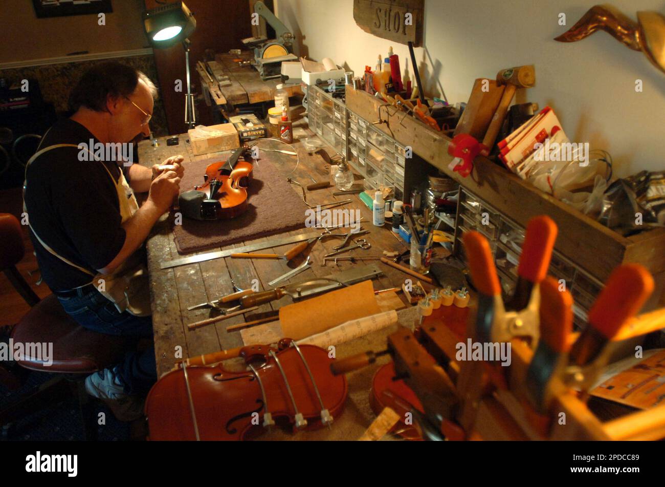 Violin repairman Buddy Squyres trims the feet of a violin bridge at his