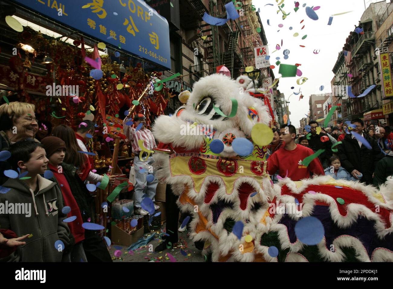 Spectators watch as members of the New York United Dragon and Lion Dance Group perform a blessing in front of a souvenir shop during a celebration of the Lunar New Year, The Year of the Dog, Sunday, Jan. 29, 2006, in New York's Chinatown. According to Chinese custom, the lion is a symbol of bravery and peace. The lion dance is performed during festivities like Chinese New Year, weddings and restaurant openings. (AP Photo/Kathy Willens) Banque D'Images