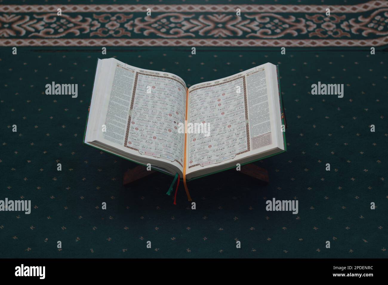 Un gros plan du livre Saint Al-Coran sur un tapis de prière vert. Concept de photo islamique. Banque D'Images
