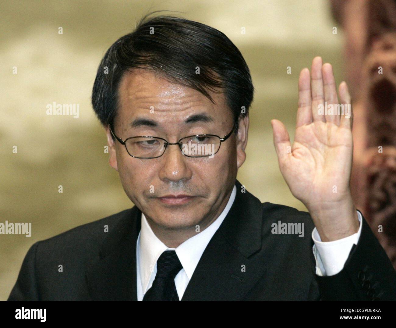 Japanese developer Huser Management Ltd. President Susumu Ojima raises his hand before responding to a lawmaker's questions during a Parliamentary hearing over a construction scam in Tokyo Tuesday, Jan. 17, 2006. The scandal has focused on architect Hidetsugu Aneha, who acknowledged ducking quake regulations on at least 21 buildings, all of which have been found at risk of collapsing in a moderately strong temblor. (AP Photo/Koji Sasahara) Banque D'Images