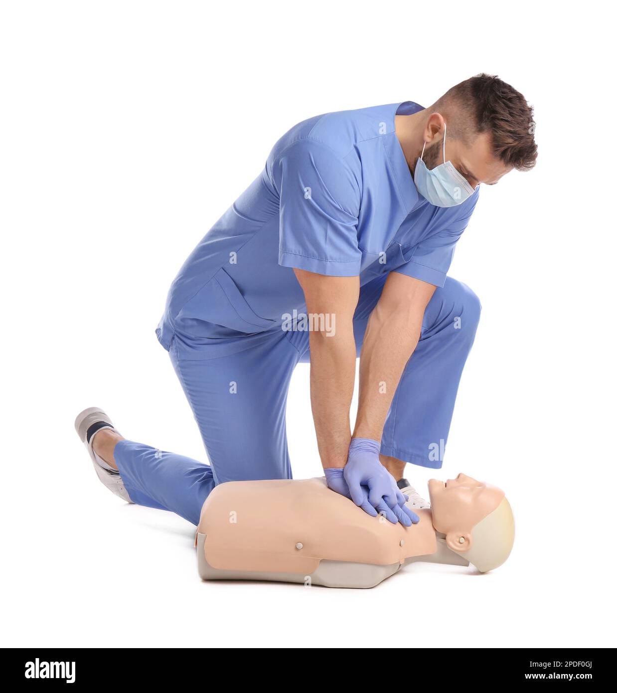 Médecin en uniforme et masque de protection pratiquant les premiers soins sur le mannequin sur fond blanc Banque D'Images