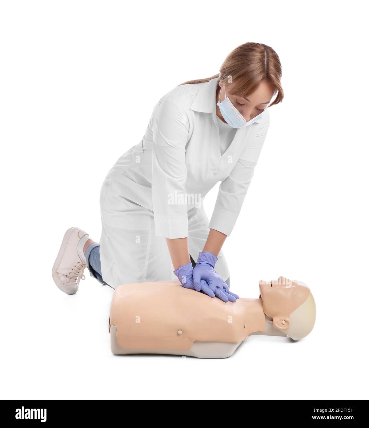 Médecin en uniforme et masque de protection pratiquant les premiers soins sur le mannequin sur fond blanc Banque D'Images