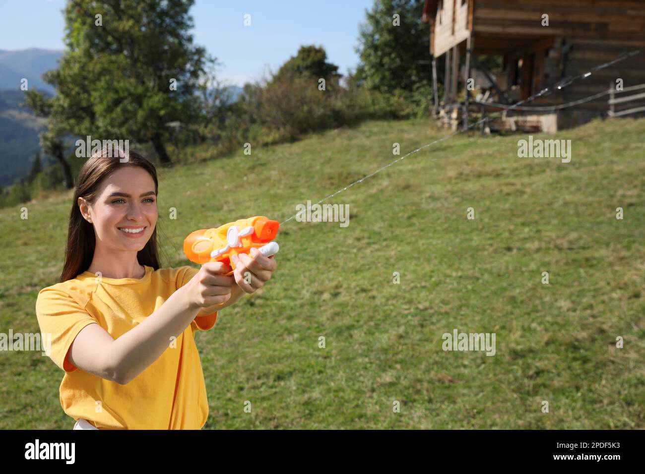 Bonne femme avec un pistolet à eau s'amusant dans les montagnes par beau temps Banque D'Images