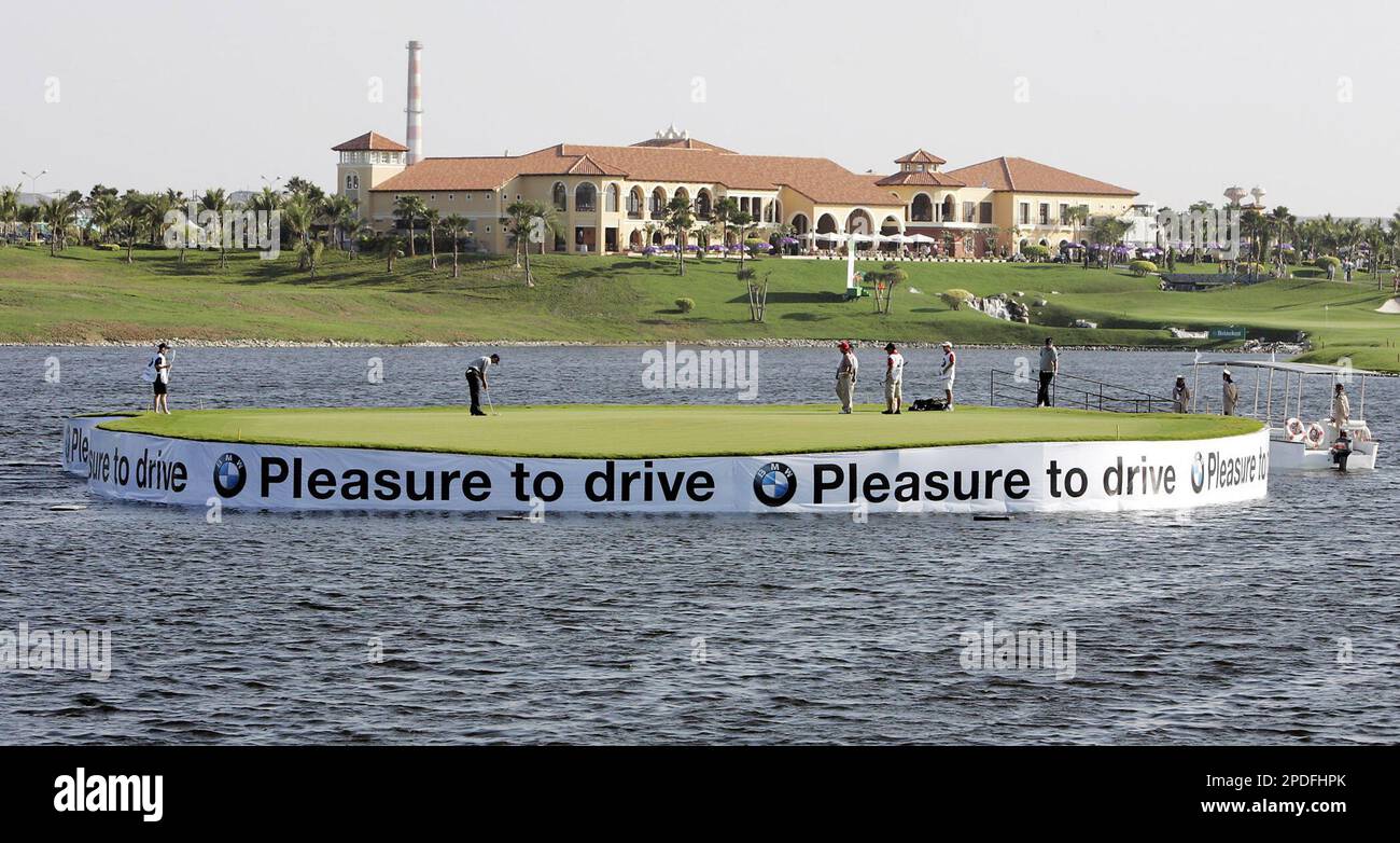 Golfers from Europe and Asia with their caddies play on the 8th green in the middle of a pond during the inaugural Royal Trophy golf match play between European and Asian golfers at the Amata Spring Country Club golf course in Chonburi province, central Thailand Saturday, Jan. 7, 2006. (AP Photo/Apichart Weerawong) Banque D'Images