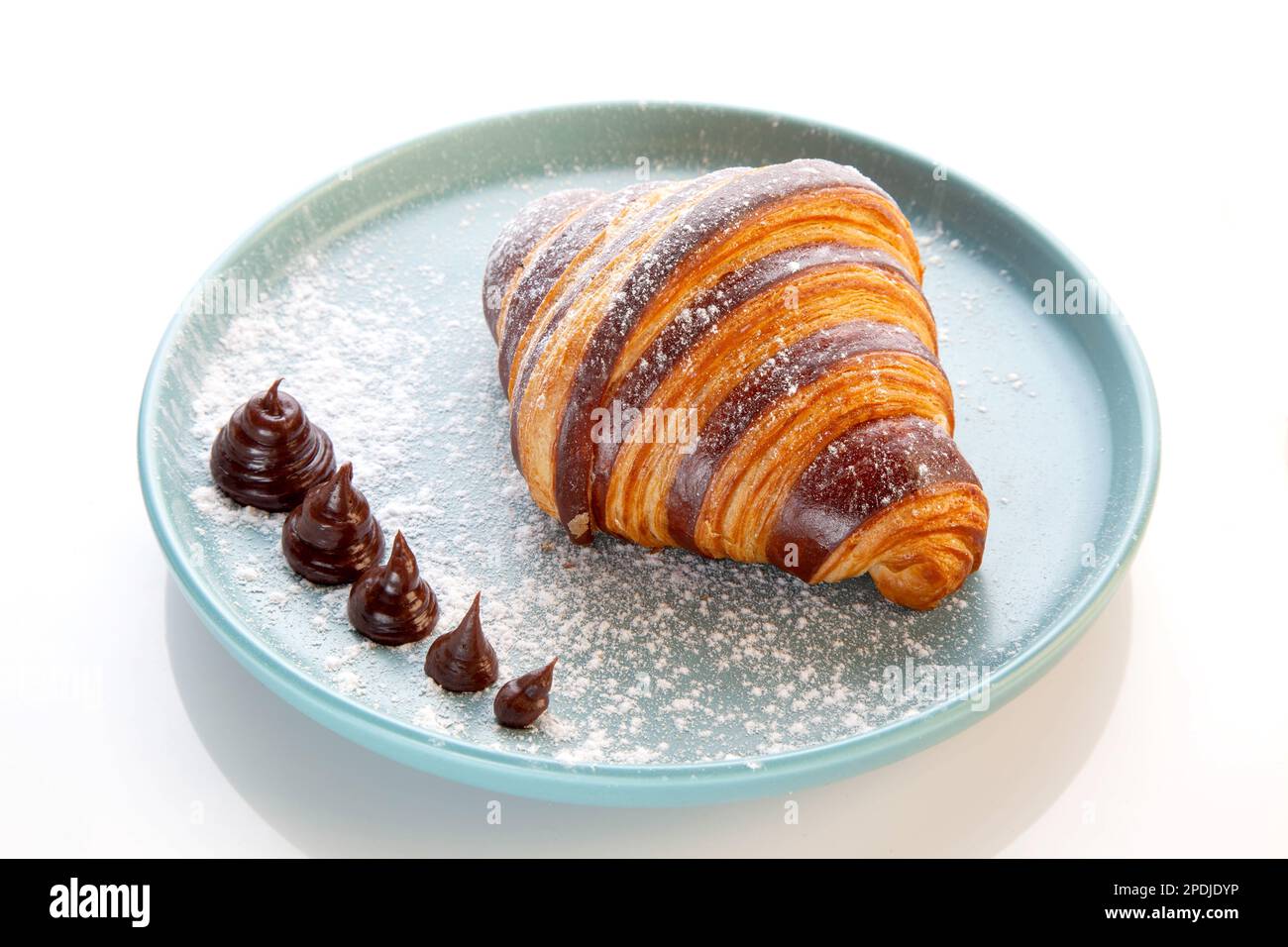 Croissant au chocolat brioche servi sur une assiette bleue. Banque D'Images