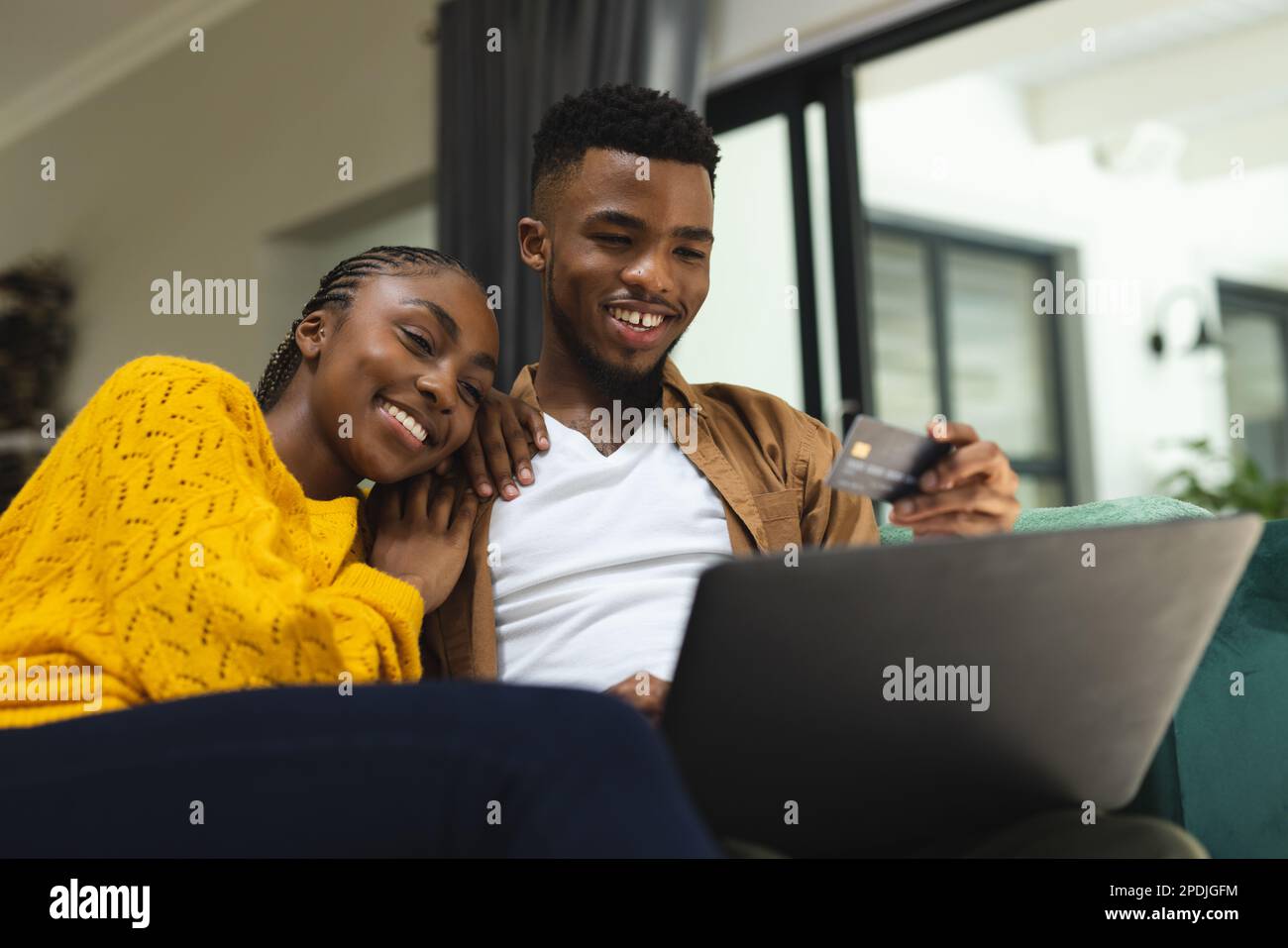 Un heureux couple afro-américain assis sur un canapé et utilisant un ordinateur portable pour faire des achats en ligne Banque D'Images