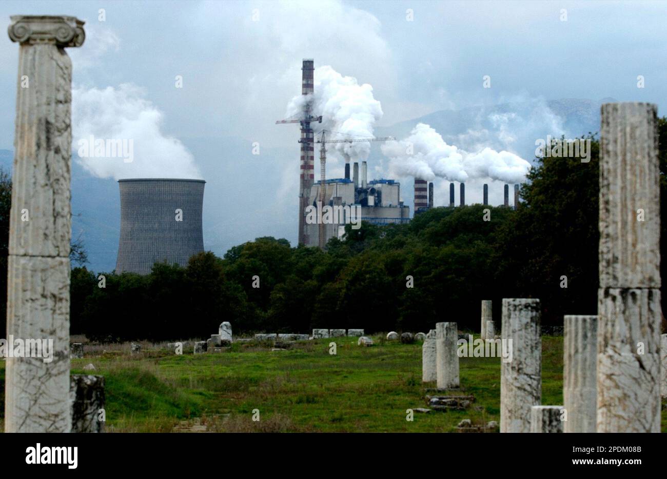 Ancient columns are seen at an archaeological site in Megalopolis, about 190 kilometers (119 miles) southwest of Athens Monday, Oct. 31, 2005, as smoke pours from one of Greece's largest power plants. Local residents said last week they planned to protest the power corporation's decision not to instal filters to limit the amount of pollution released into the air by the plant. (AP Photo/Thanassis Stavrakis) Banque D'Images
