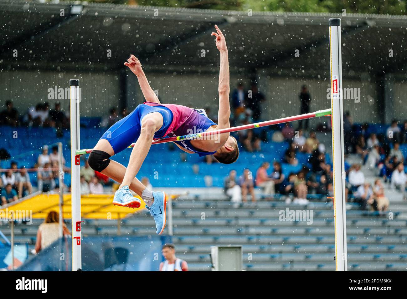 Pull d'athlète pour homme saut en hauteur sous la pluie, compétition d'athlétisme, chaussures Nike Spikes pour saut, photos de sport Banque D'Images