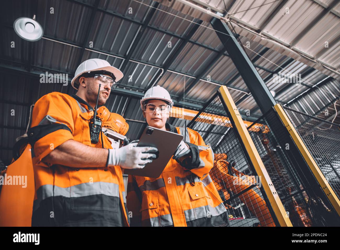 L'équipe d'ingénieurs assure le service de soudage des robots travaillant dans l'usine d'automatisation. Les personnes travaillant en costume de sécurité travaillent robotique ARM logiciel de programmation ou de remplacement par Banque D'Images