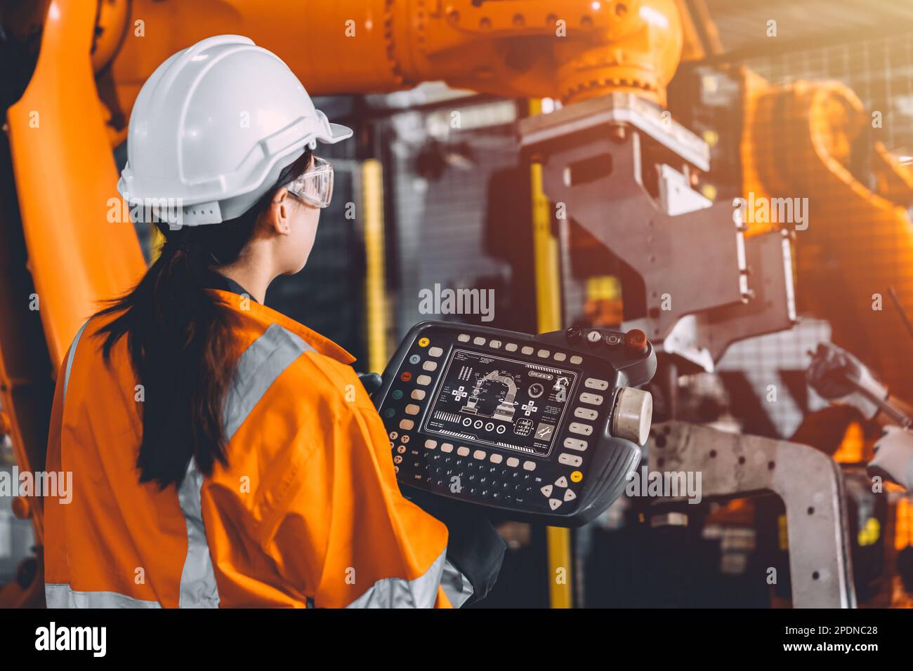 L'équipe d'ingénieurs assure le service de soudage des robots travaillant dans l'usine d'automatisation. Une femme utilise le contrôleur manuel du logiciel du bras robotique dans un fabricateurautomatisé Banque D'Images