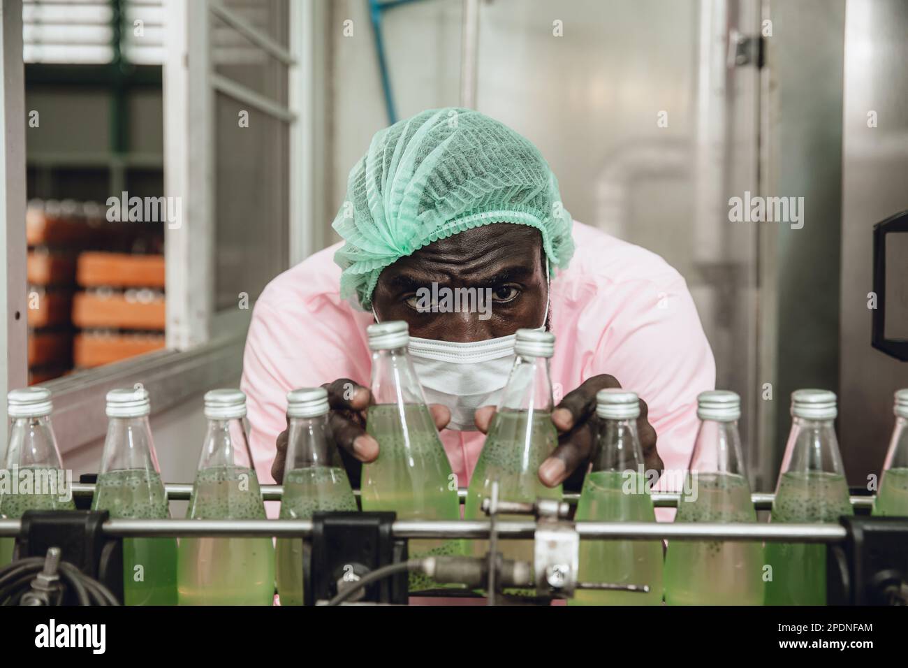 Un employé nigérian africain travaille au contrôle de la qualité de l'usine de boissons sur la ligne de produits du tapis roulant Banque D'Images