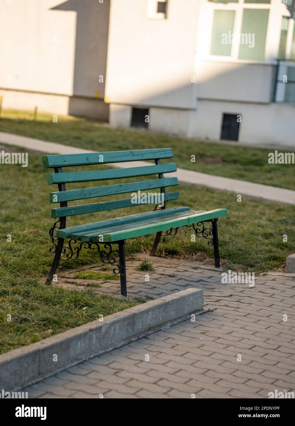 Un banc de parc vert se trouve sur la pelouse en face d'une maison de banlieue. Banque D'Images