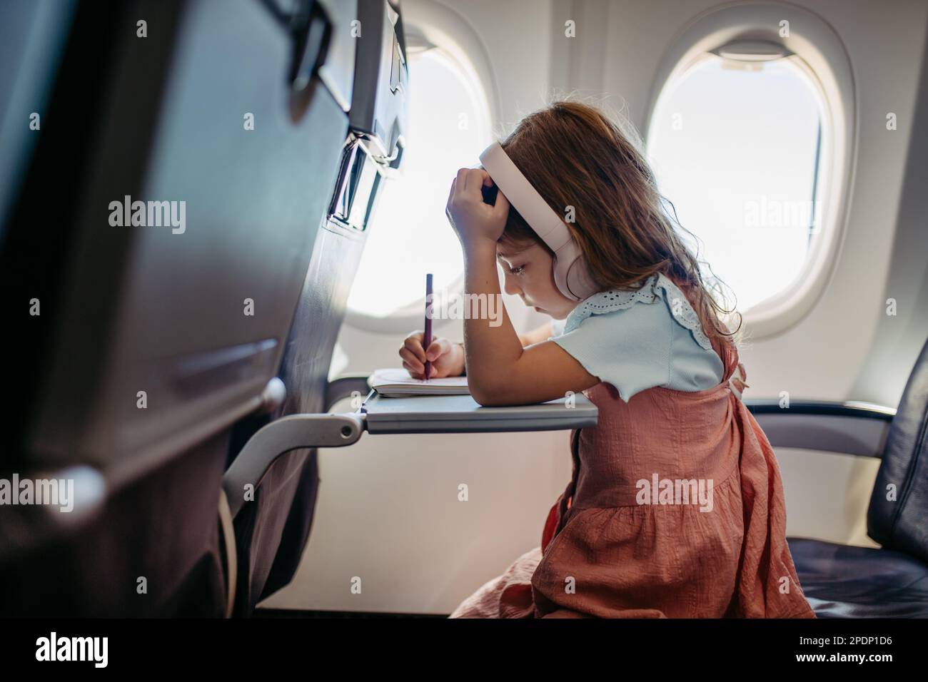 Petite fille en avion dessin et musique d'écoute. Banque D'Images