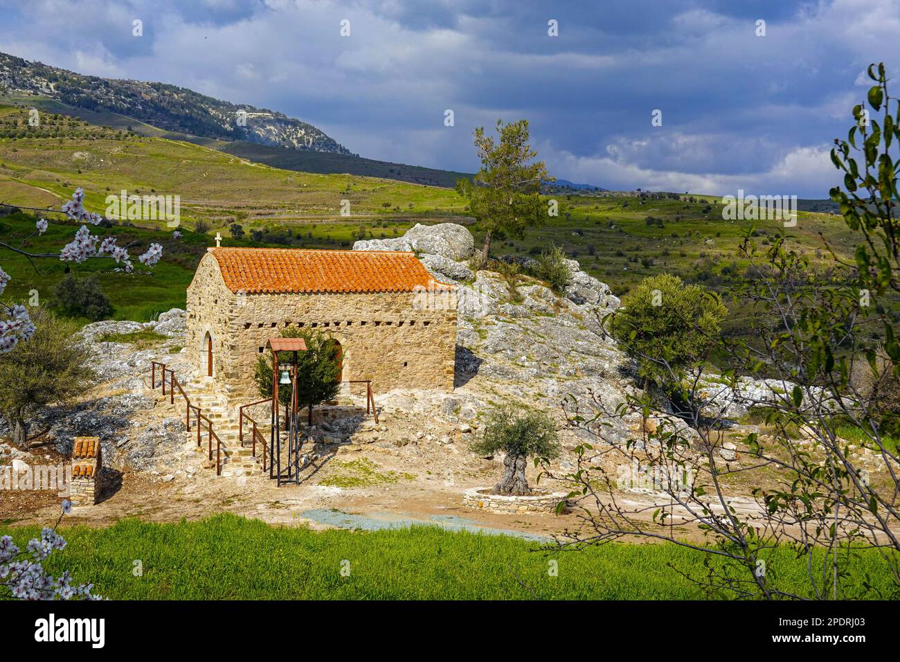Petite chapelle par rocher avec toit de tuiles rouges et cloche, à l'intérieur des terres de la région de Phaphos Pafos de Chypre en hiver, soleil d'hiver Banque D'Images