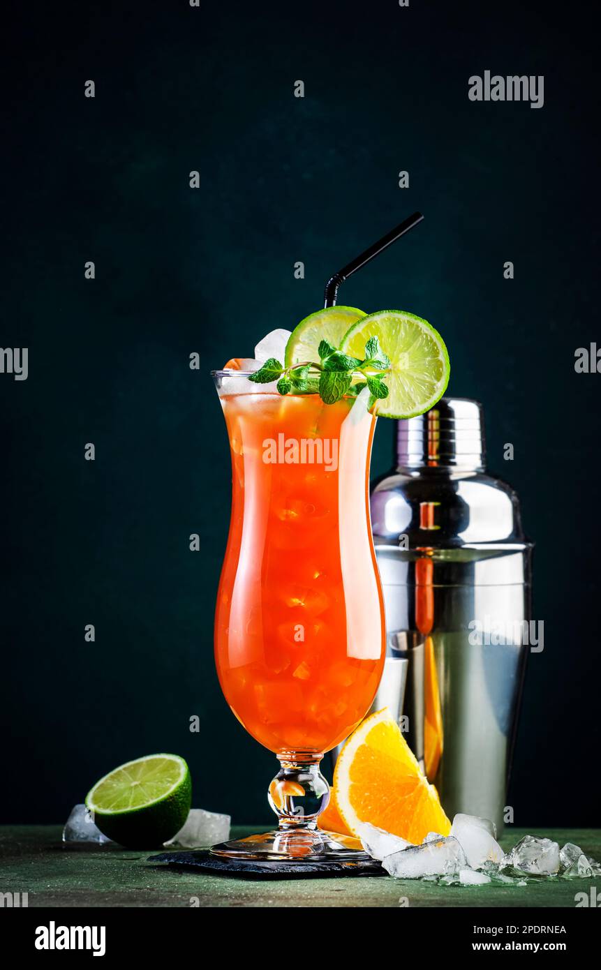 Cocktail alcoolisé Hurricane avec rhum noir et blanc, glace, grenadine, jus  d'ananas et d'orange, citron vert et glace, garni de menthe. Arrière-plan  sombre Photo Stock - Alamy