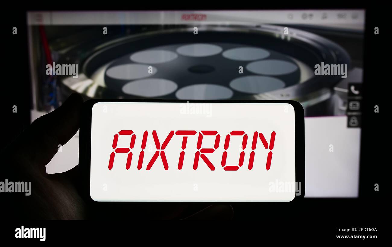 Personne tenant un smartphone avec le logo de la société de technologie allemande Aixtron se sur l'écran devant le site Web. Mise au point sur l'affichage du téléphone. Banque D'Images