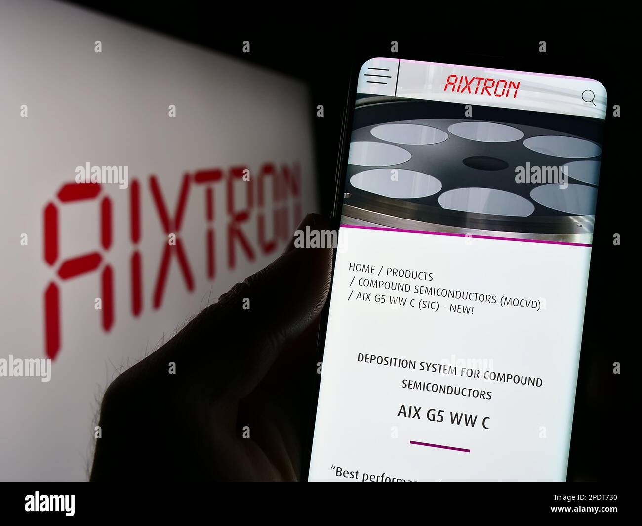 Personne tenant un smartphone avec la page Web de la société allemande de technologie Aixtron se à l'écran devant le logo. Concentrez-vous sur le centre de l'écran du téléphone. Banque D'Images