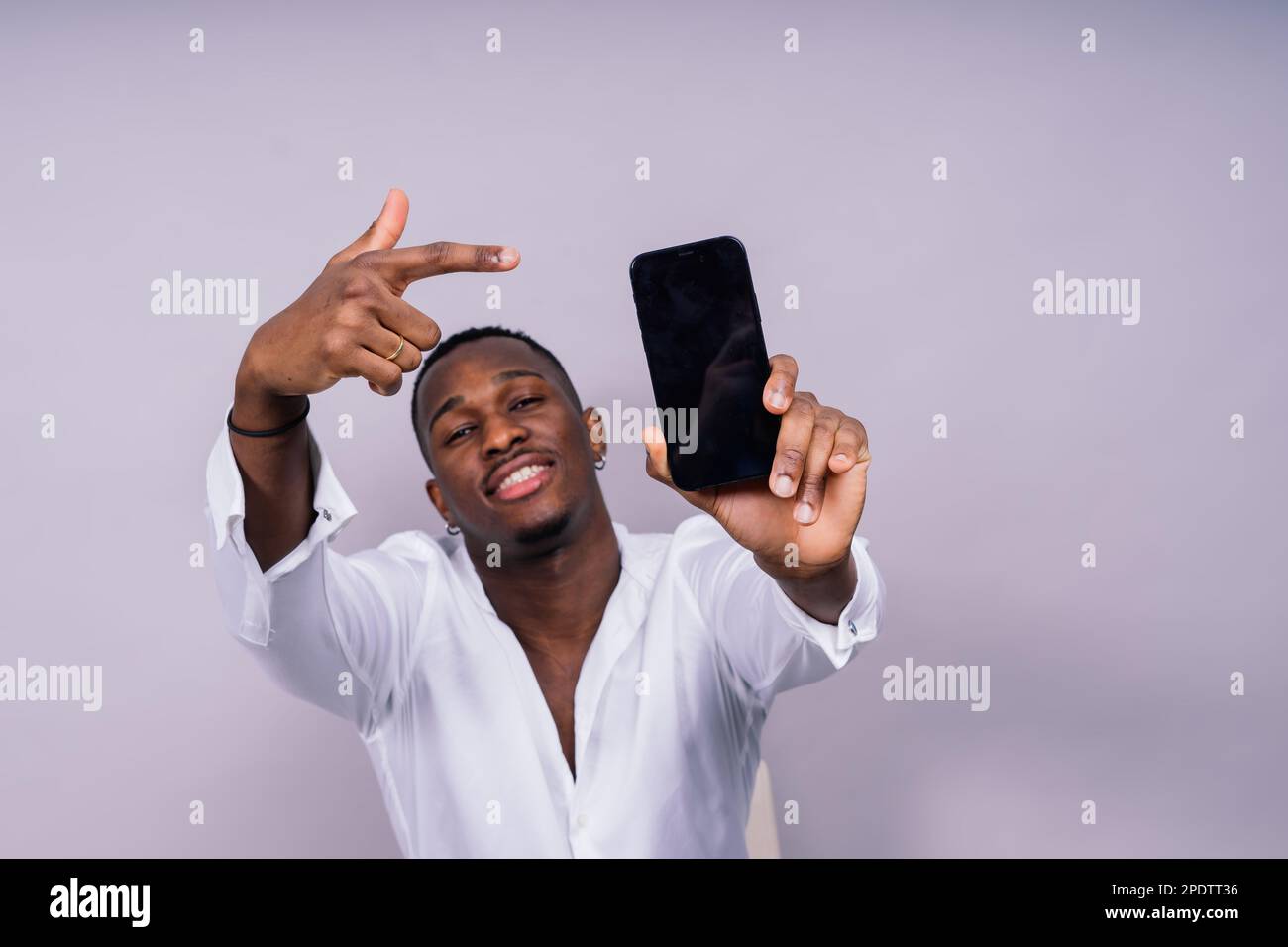 Beau jeune homme d'affaires africain excité avec un téléphone portable isolé sur fond gris Banque D'Images