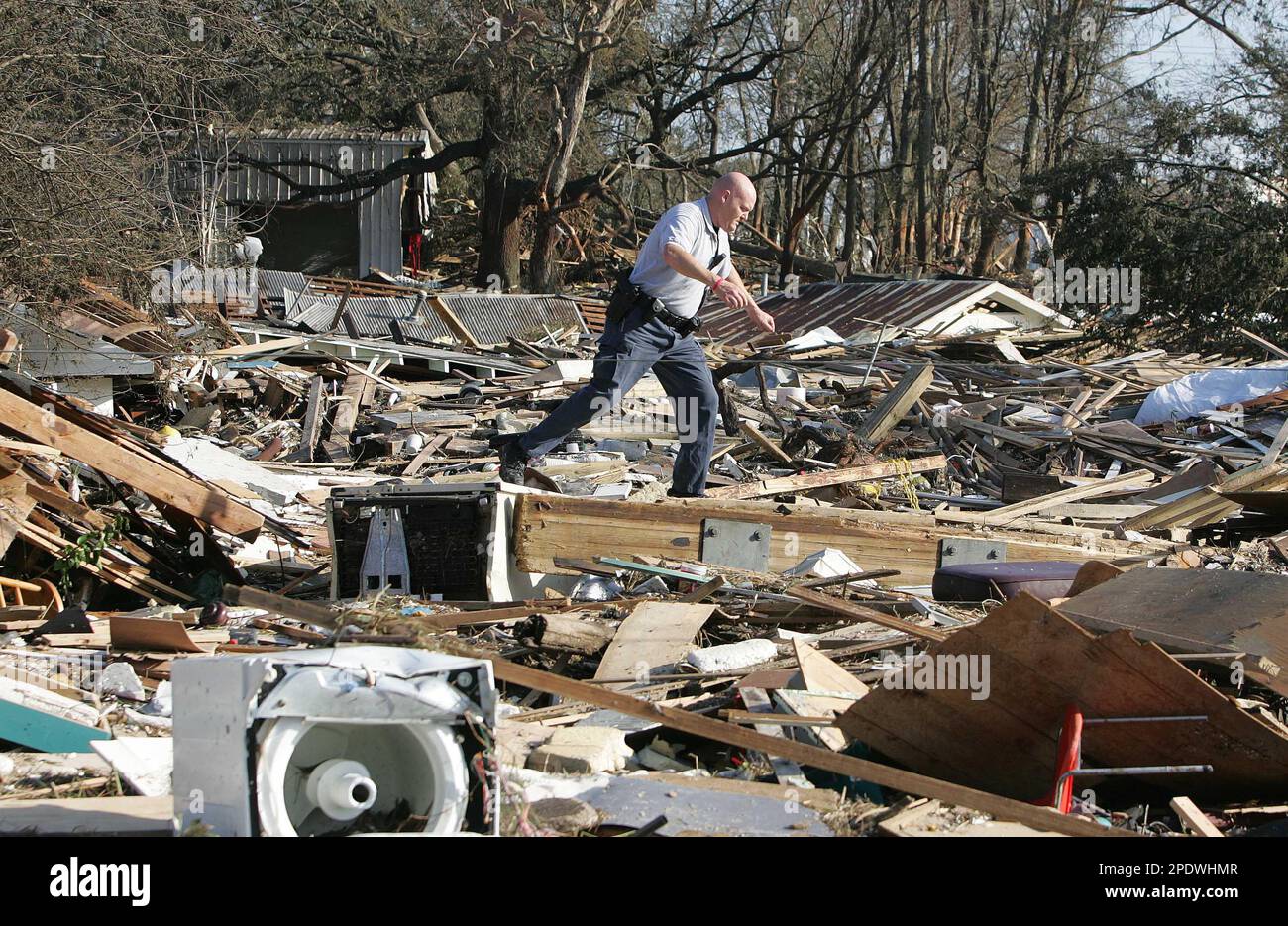 ** RETRANSMITTED TO CORRECT OBJECT NAME ** Harrison County Sheriff's deputy Ray Wescovich climbs over debris after checking on an elderly neighbor who's home was destroyed by Hurricane Katrina Tuesday, Aug. 30, 2005 in Biloxi, Miss. Wescovich said his home was destroyed in the storm. (AP Photo/John Bazemore) Banque D'Images