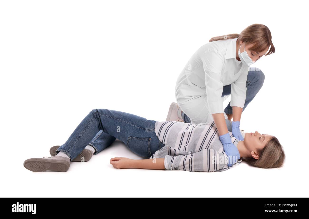 Médecin en uniforme et masque de protection effectuant les premiers soins sur une femme inconsciente sur fond blanc Banque D'Images