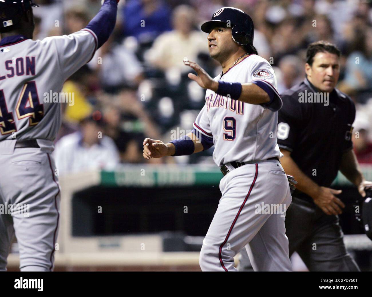 Washington Nationals' Preston Wilson, left, congratulates teammate Vinny Castilla, center, as he crosses home plate after scoring on a double hit by Brian Schneider in the fourth inning against the Colorado Rockies in Denver, Friday, Aug. 12, 2005. Home plate umpire Tony Randazzo, right, looks on. (AP Photo/David Zalubowski) Banque D'Images
