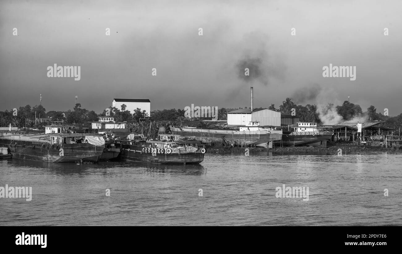 Des péniches motorisées amarrées sur le côté du Mékong à côté des usines et de la pollution près de long Xuyen dans le delta du Mékong, au Vietnam. Banque D'Images
