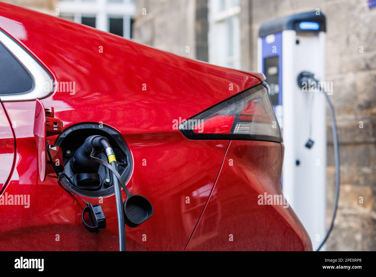 Un véhicule électrique rouge est branché à une unité de charge électrique de ChargePlace Scotland sur le campus de l'Université d'Édimbourg. Banque D'Images