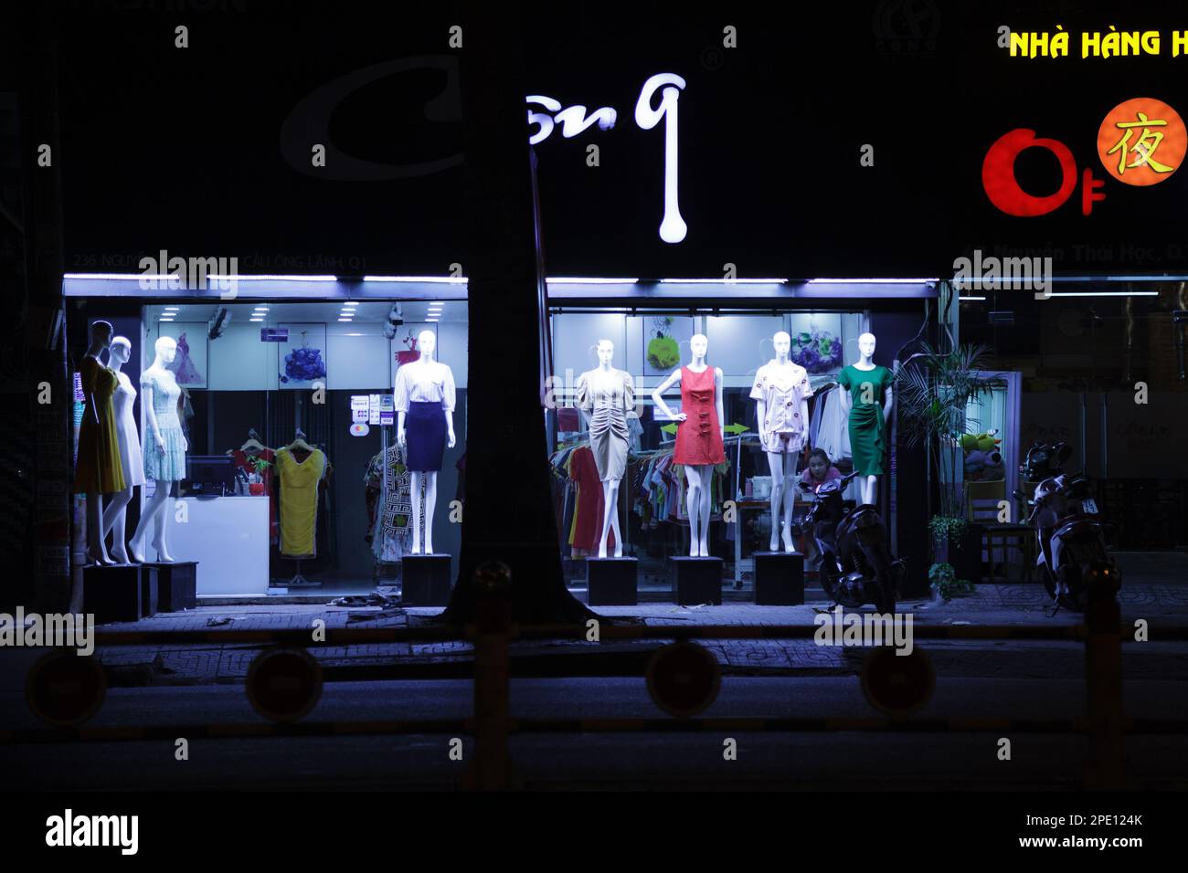 Ho Chi Minh ville, Vietnam - 8 mai 2020 : robes pour femmes exposées sur des mannequins devant un magasin de mode. Jeune asiatique vendeuse seule dans un vêtement b Banque D'Images