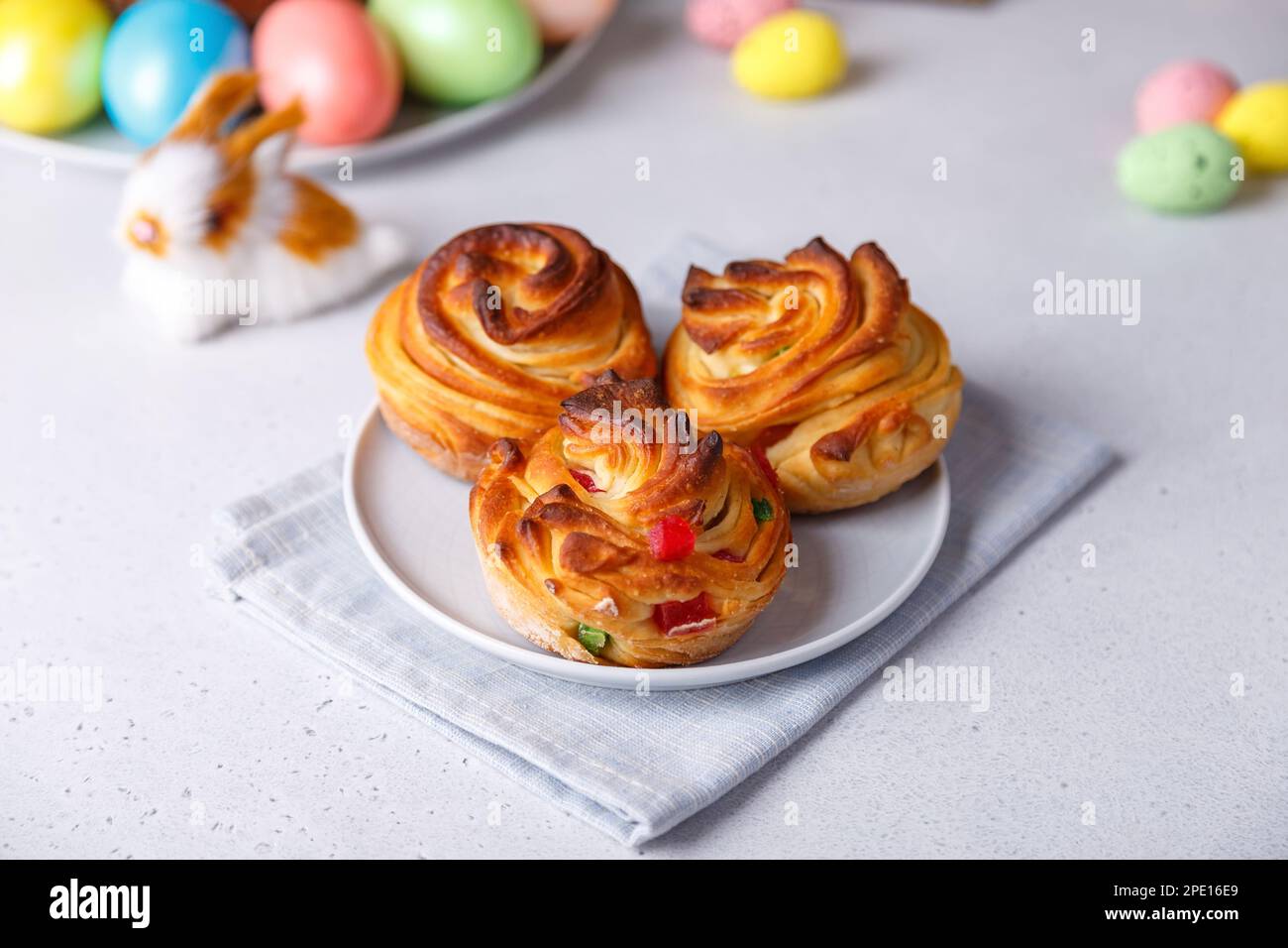 Mini-Craffin (Craffin) avec raisins secs et fruits confits. Gâteau traditionnel de Pâques. En arrière-plan sont des oeufs peints et un lapin de Pâques. Banque D'Images