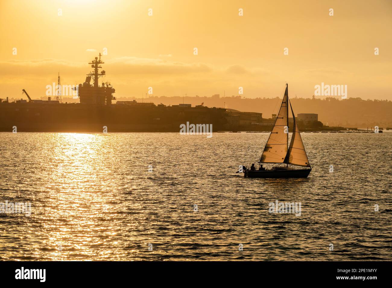 Bateau Sainling au coucher du soleil à San Diego, navire militaire en arrière-plan Banque D'Images