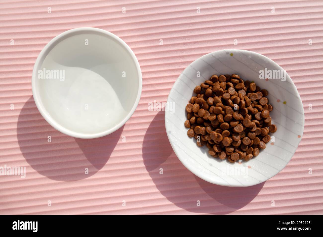 Bols en céramique pour animaux de compagnie remplis d'eau et de nourriture sèche vue sur le dessus. Plats pour nourrir un chat ou un chien avec des croquettes croquantes et de l'eau douce Banque D'Images