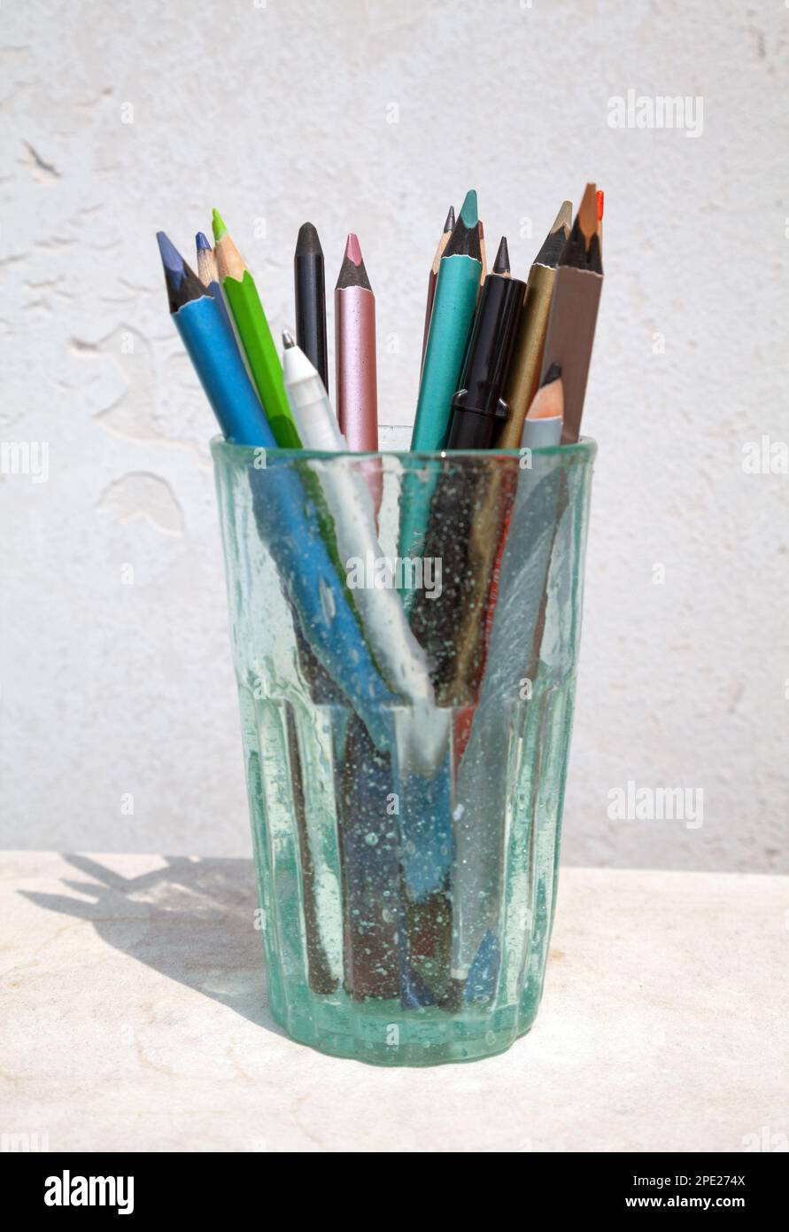 Ensemble de crayons de couleur assortis et autres outils d'art stockés dans un verre. Matériel d'artiste pour le dessin Banque D'Images