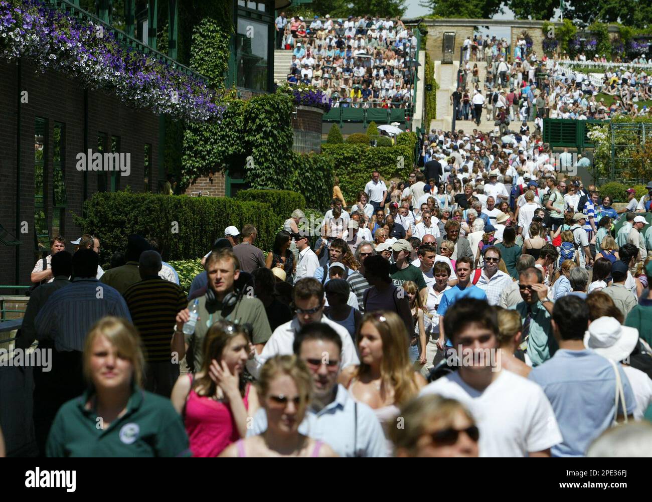 Tennis fans throng the walkways alongside the courts at Wimbledon, in bright sunshine on the second day of the 2005 tournament, Tuesday, June 21, 2005, highlighting the All England Lawn Tennis Club's concept of the All England Lawn Tennis Championships as "tennis in an English country garden".(AP Photo/Franka Bruns) Banque D'Images