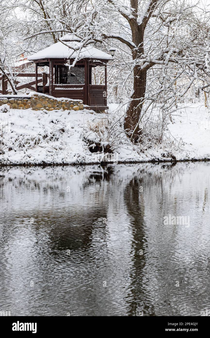 Un petit belvédère en bois dans les profondeurs d'une forêt d'hiver près d'un ruisseau de montagne froid et noyés marchent le long de lui, grimpant d'une vallée forestière. Banque D'Images