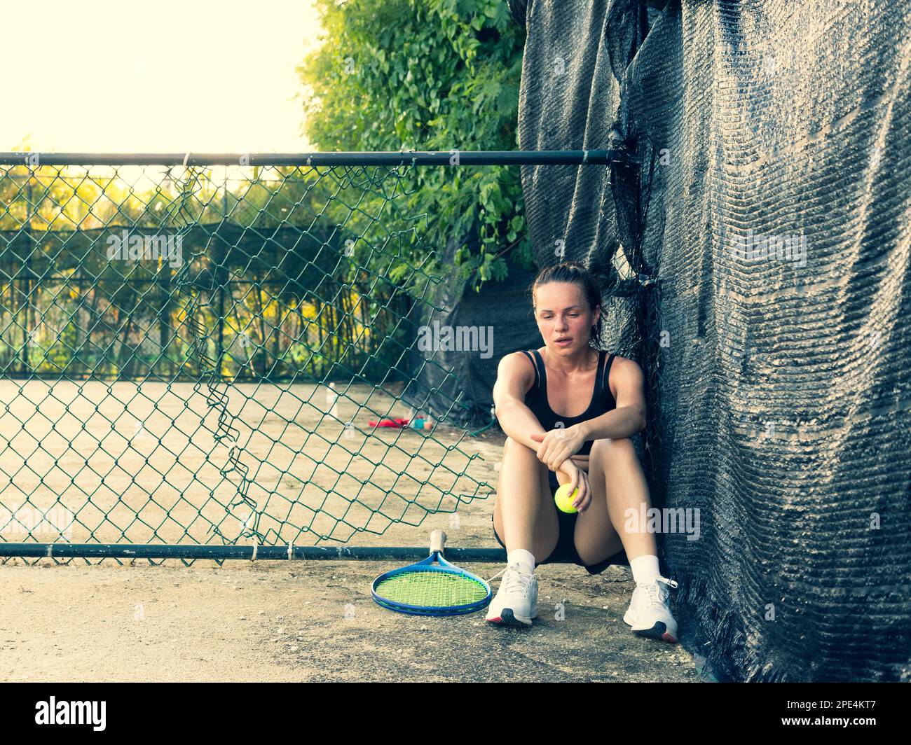 Une joueuse de tennis triste et fatiguée se trouve sur le terrain d'un court de tennis après un match. Banque D'Images
