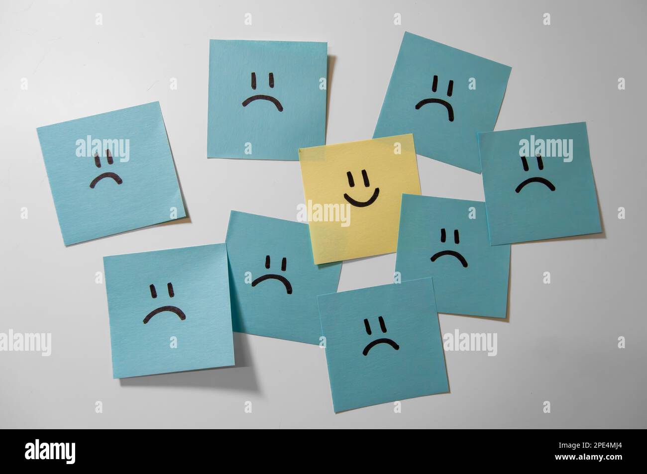 Collez des notes sur le fond blanc. Papiers pense-bête avec smiley. L'un est différent. Un visage souriant heureux parmi les plus tristes. Banque D'Images