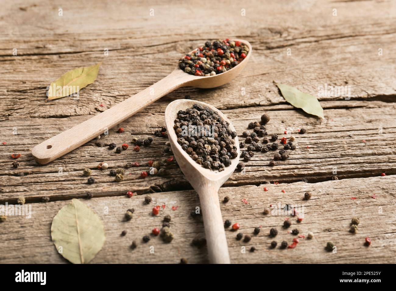 Mélanger les poivrons et les pois dans une cuillère en bois sur fond de bois, vue du dessus. Poivron rouge, poivre blanc et poivre vert. Banque D'Images