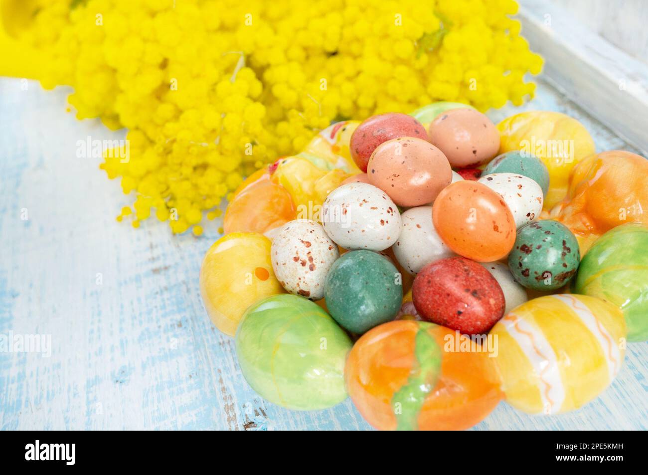 œufs de pâques avec mimosa. Vacances de Pâques mimosa fleurs décorées avec des oeufs colorés. Bonbons au chocolat avec glaçage sous forme d'œufs de caille sur un bon Banque D'Images