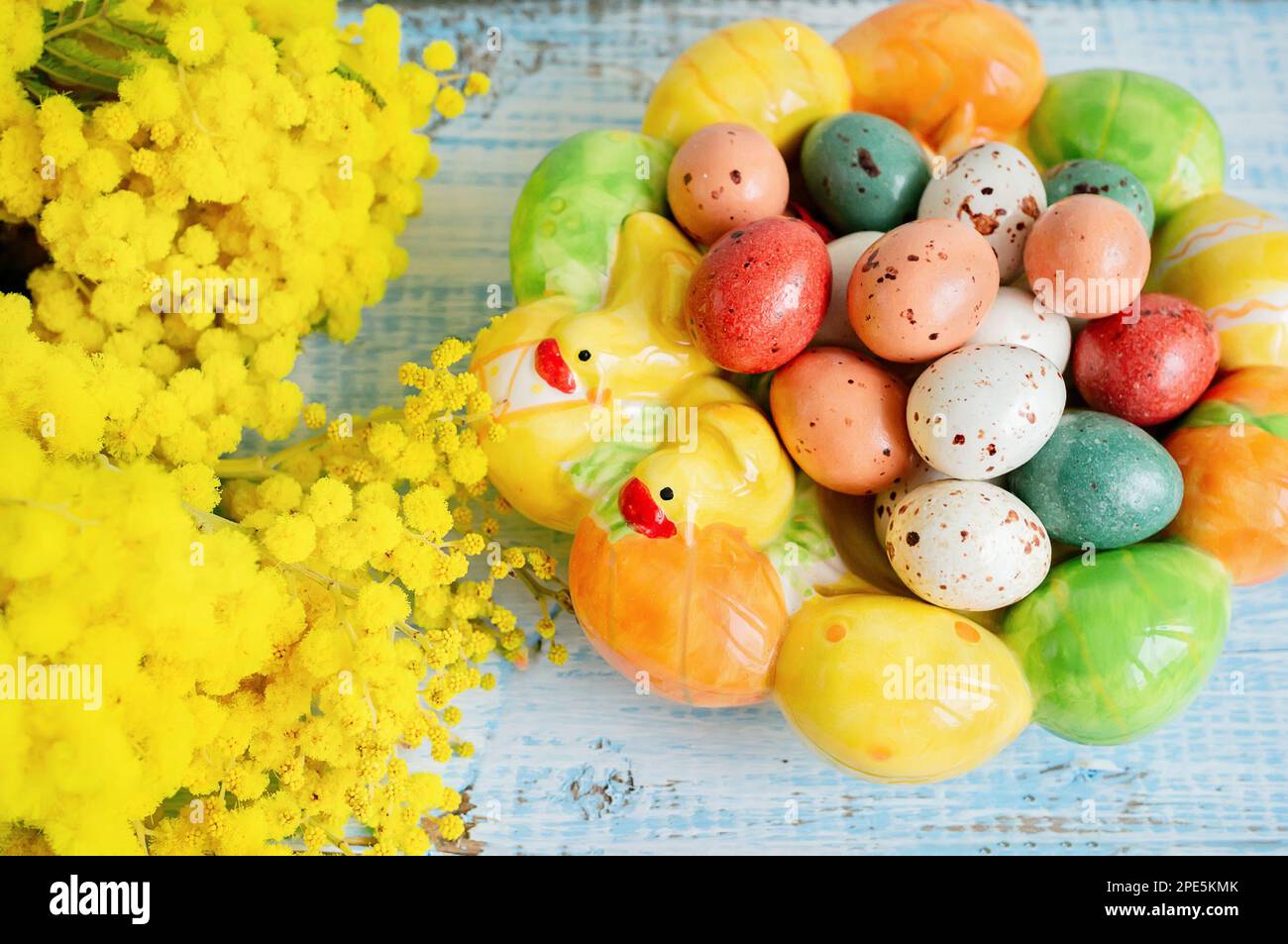 œufs de pâques avec mimosa. Vacances de Pâques mimosa fleurs décorées avec des oeufs colorés. Bonbons au chocolat avec glaçage sous forme d'œufs de caille sur un bon Banque D'Images