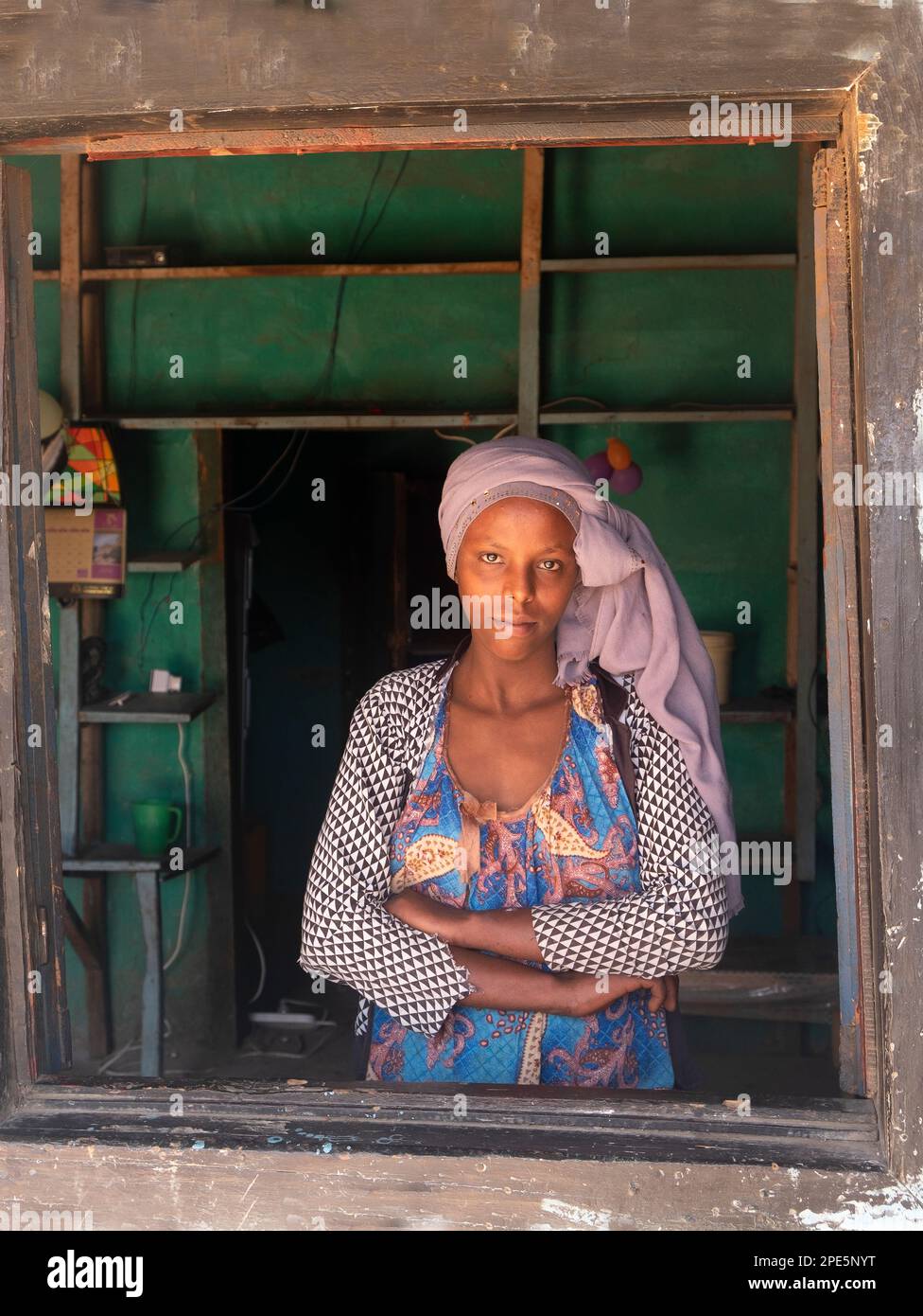 Portrait d'une femme éthiopienne dans des vêtements traditionnels derrière une fenêtre regardant l'appareil photo. Photos de la vie quotidienne. Harar est de l'Éthiopie Banque D'Images