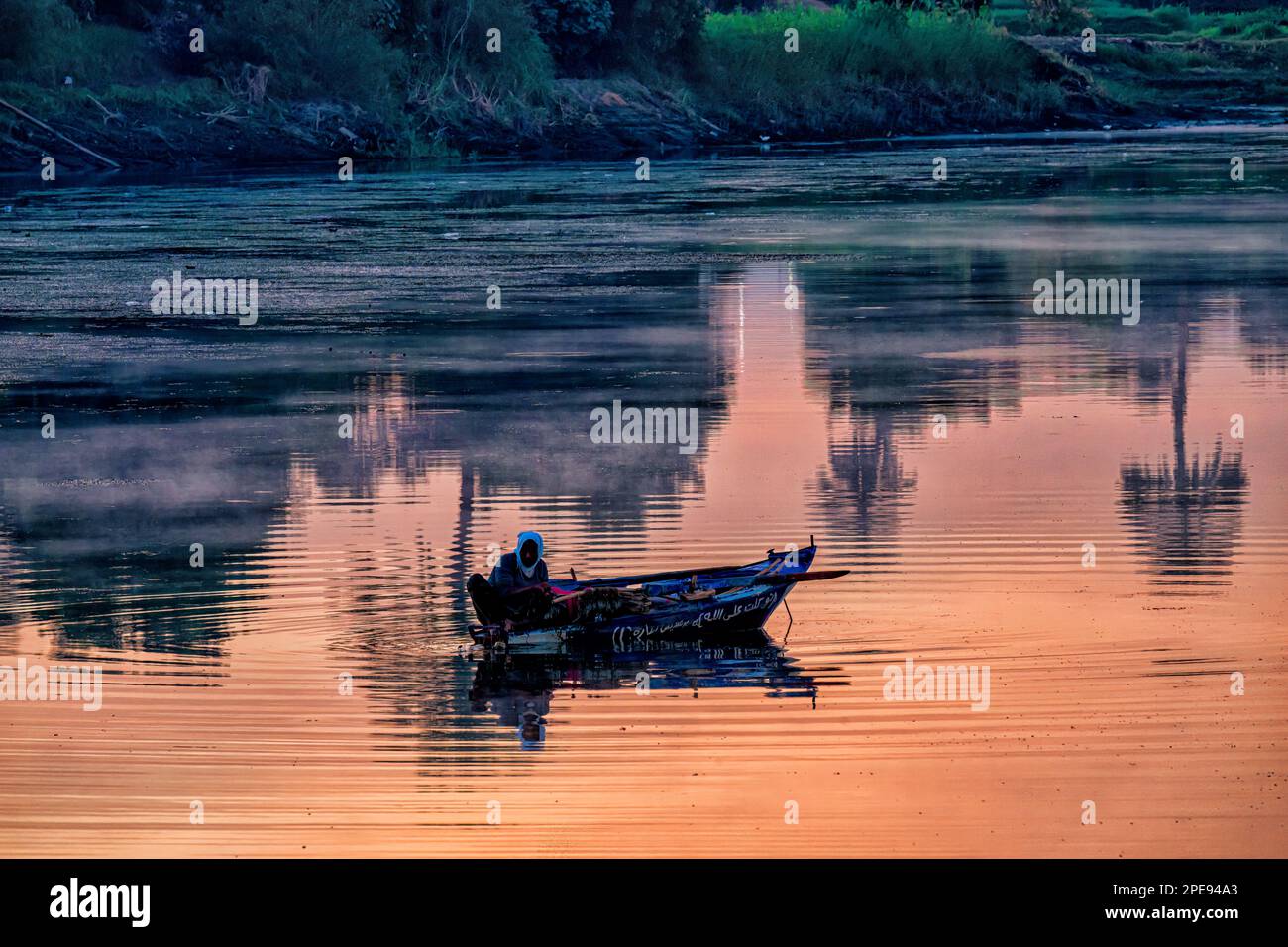 Le pêcheur rassemble son filet au lever du soleil sur le Nil à Louxor Banque D'Images
