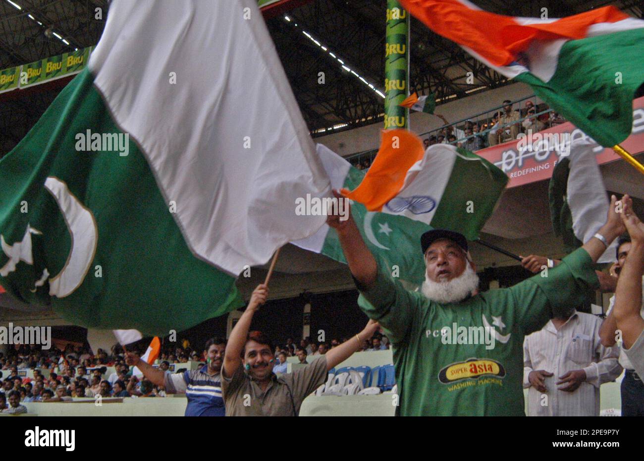 Abdul Jalil, 57, center, also known as 'Chacha Pakistani' (Pakistani Uncle) waves the Pakistani National Flag in support of the Pakistani cricketers along with other cricket fans during the second day of the third and final test match in Bangalore, India, Friday, March 25, 2005. (AP Photo/Gautam Singh) Banque D'Images