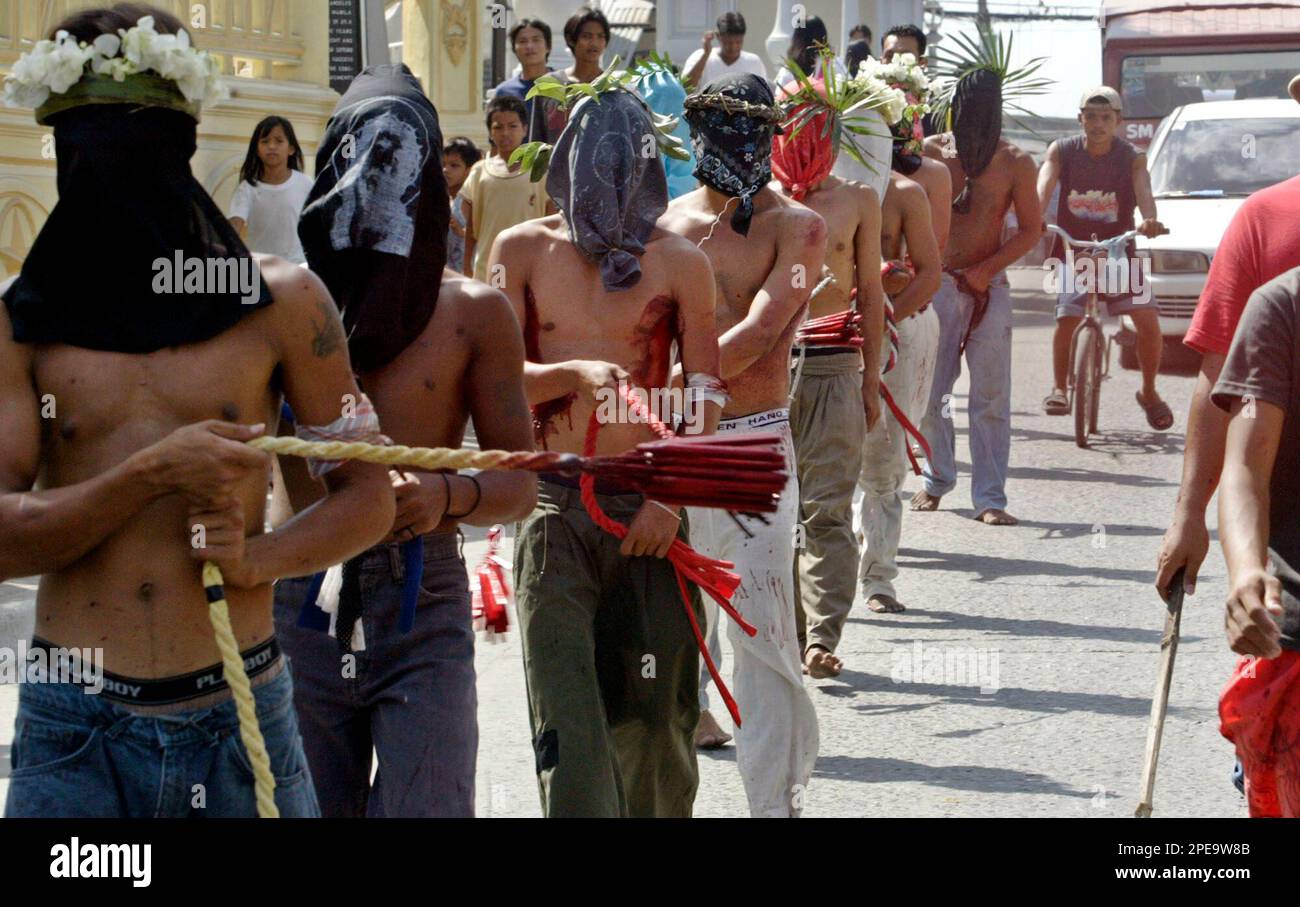Hooded Filipino penitents flagellate themselves as they make the rounds of the streets of San Fernando city in Pampanga province 70 kilometers (43 miles) north of Manila, Philippines in observance of Lent on Thursday March 24, 2005. The ritual retraces the sufferings of Jesus Christ while carrying the cross before being crucified and is being practiced in modern days as a way to atone for their sins. (AP Photo/Bullit Marquez) Banque D'Images