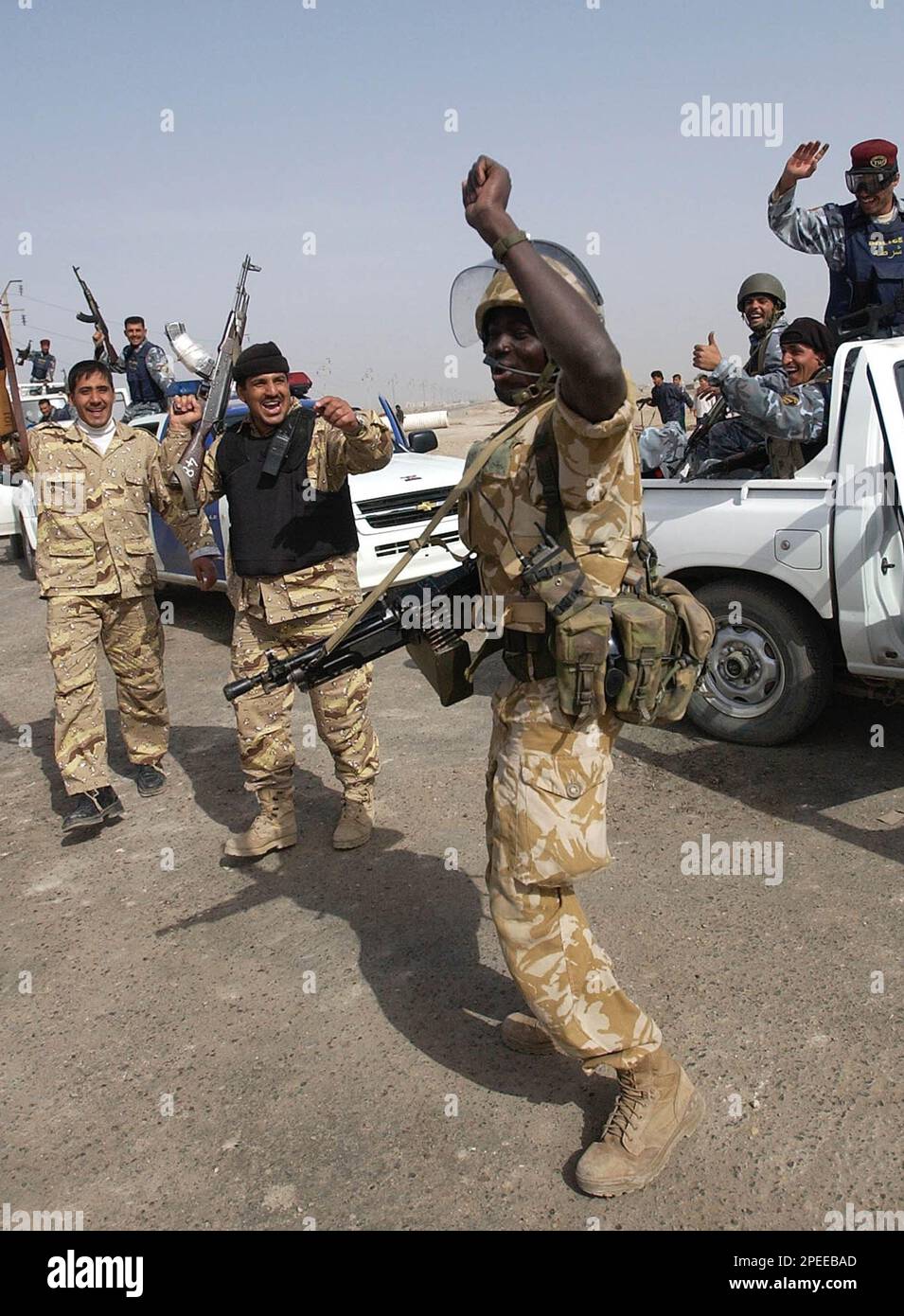 Iraqi police and a British soldier celebrate a day after the Iraqi elections in southern city of Basra, Monday, Jan. 31, 2005. A day after the vote, jubilant Iraqis sifted through ballots, tallying the results of an election that millions hoped would lead to democracy and hasten the departure of 150,000 American troops. (AP Photo/Nabil Aljurani) Banque D'Images