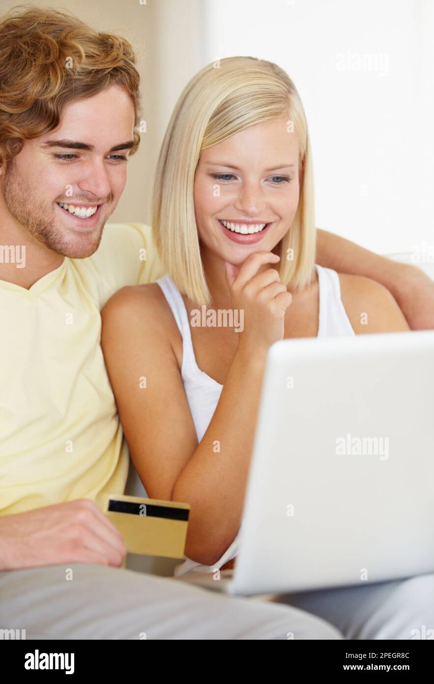 C'est exactement ce que je veux. Un jeune couple heureux faisant leur banque en ligne depuis le confort de leur canapé. Banque D'Images
