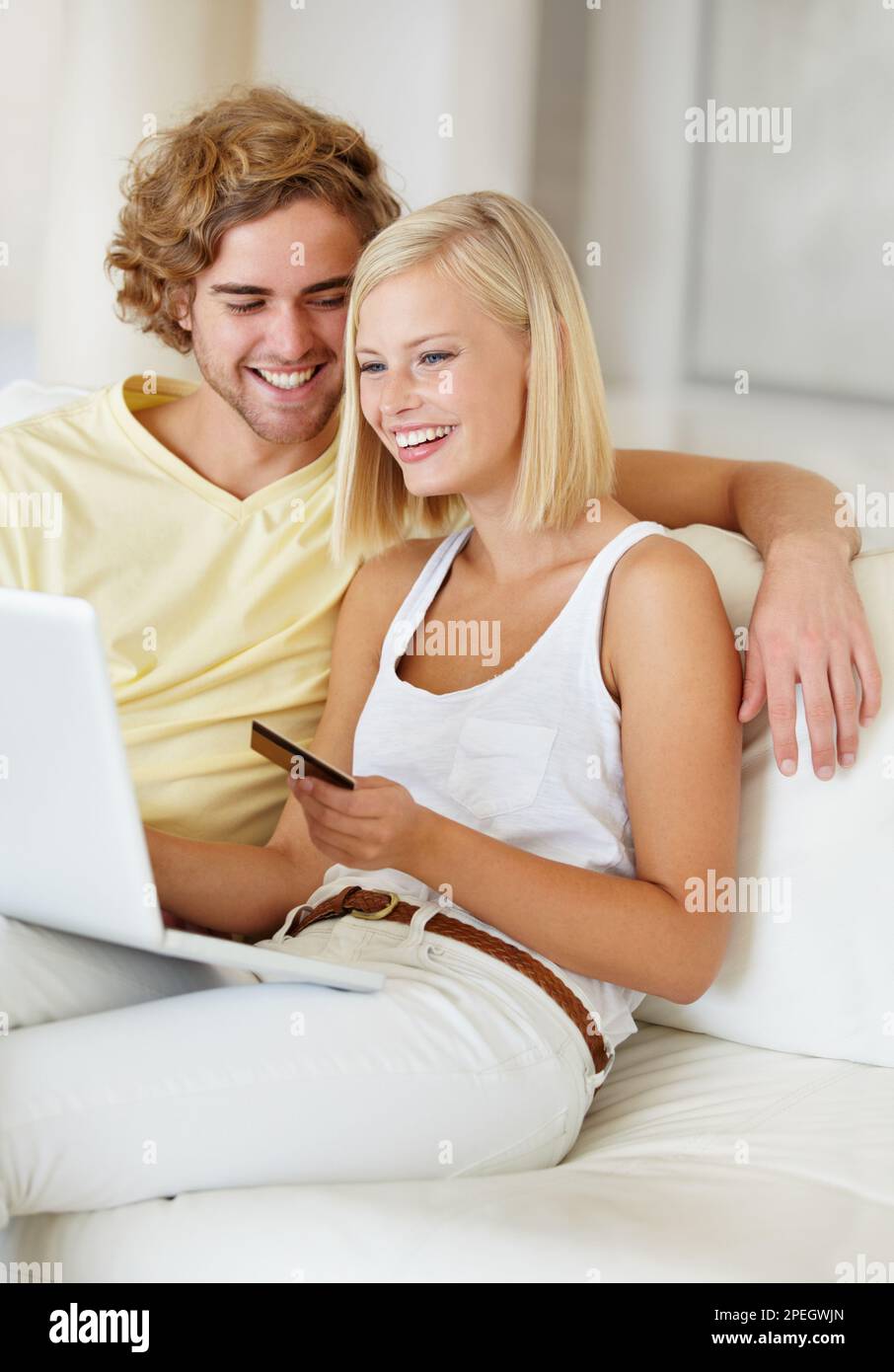 C'est possible. Un jeune couple heureux faisant leur banque en ligne depuis le confort de leur canapé. Banque D'Images